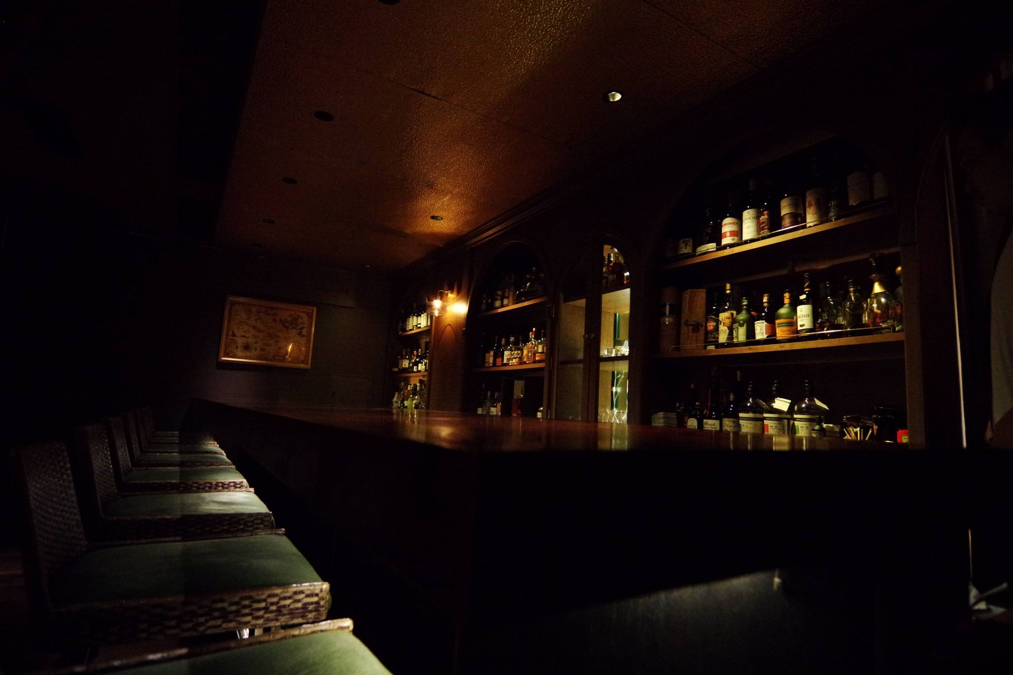 暖かな照明に包まれたBar Lampのカウンターとラム酒のボトル